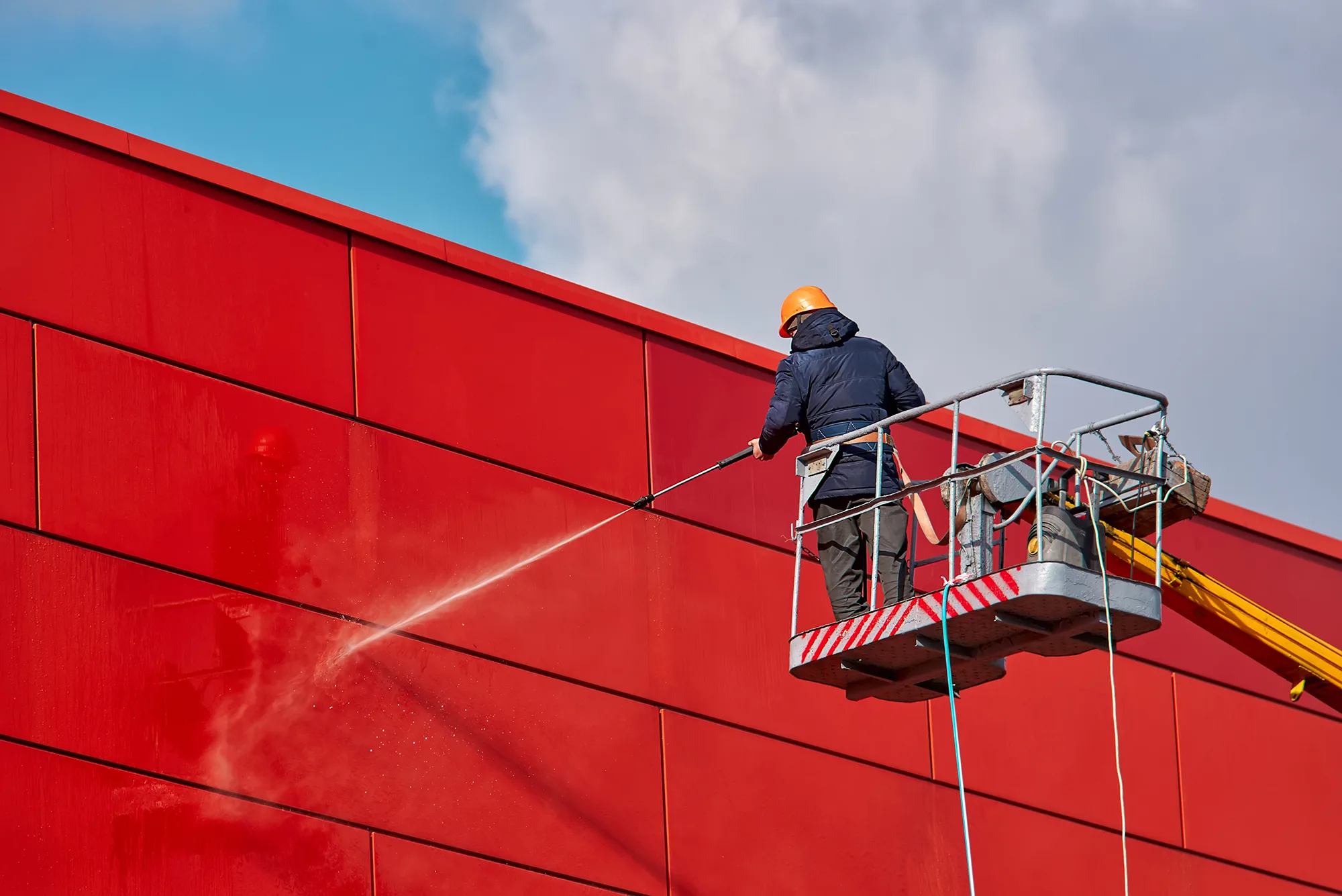 pressure washing a building from a lift